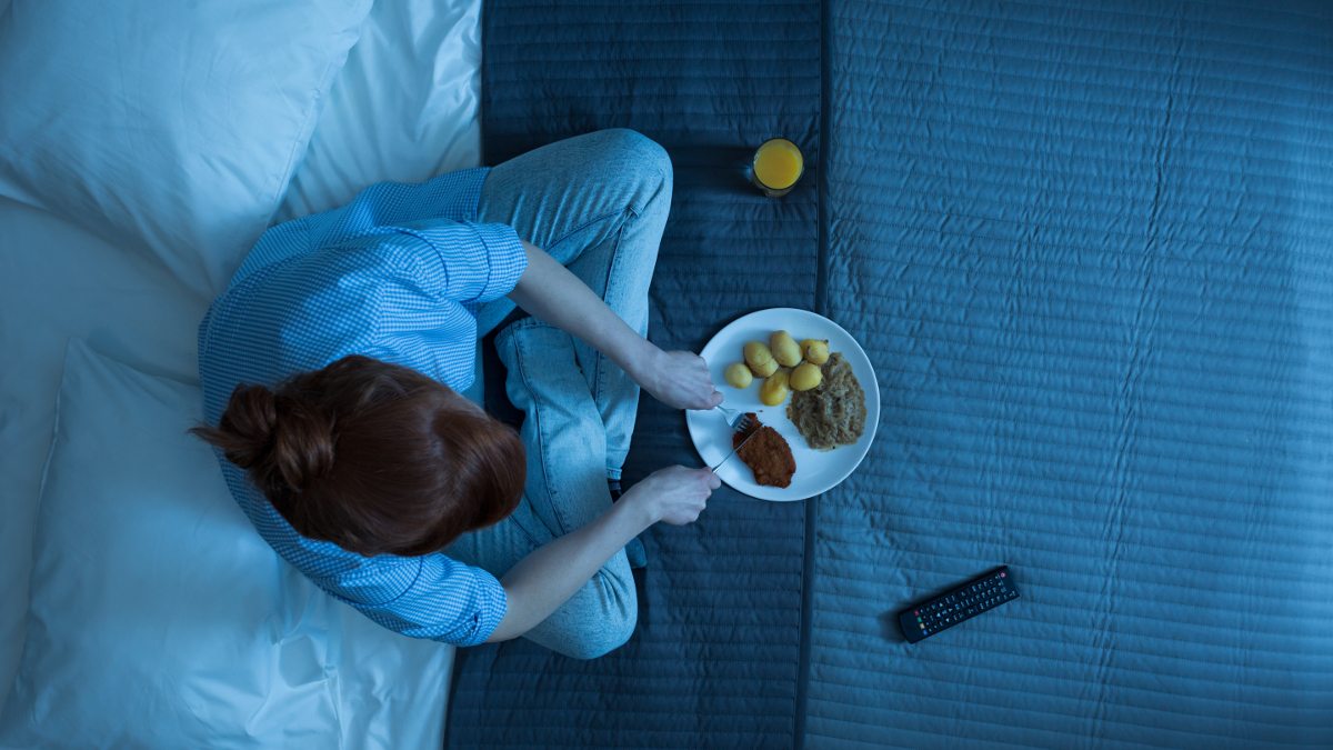 Donna che mangia di notte sul suo letto