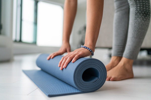 femme roulant un tapis de yoga